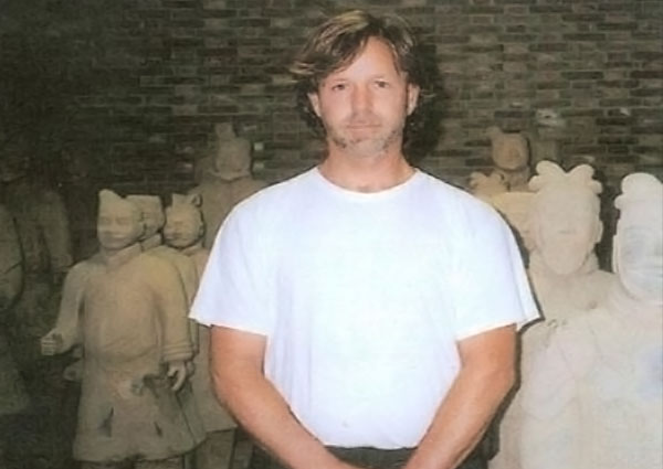Greg Morris standing in front of traditional statues