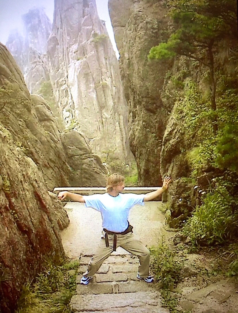 Greg Morris practicing the Single Whip Tai Chi posture on a mountain stone path